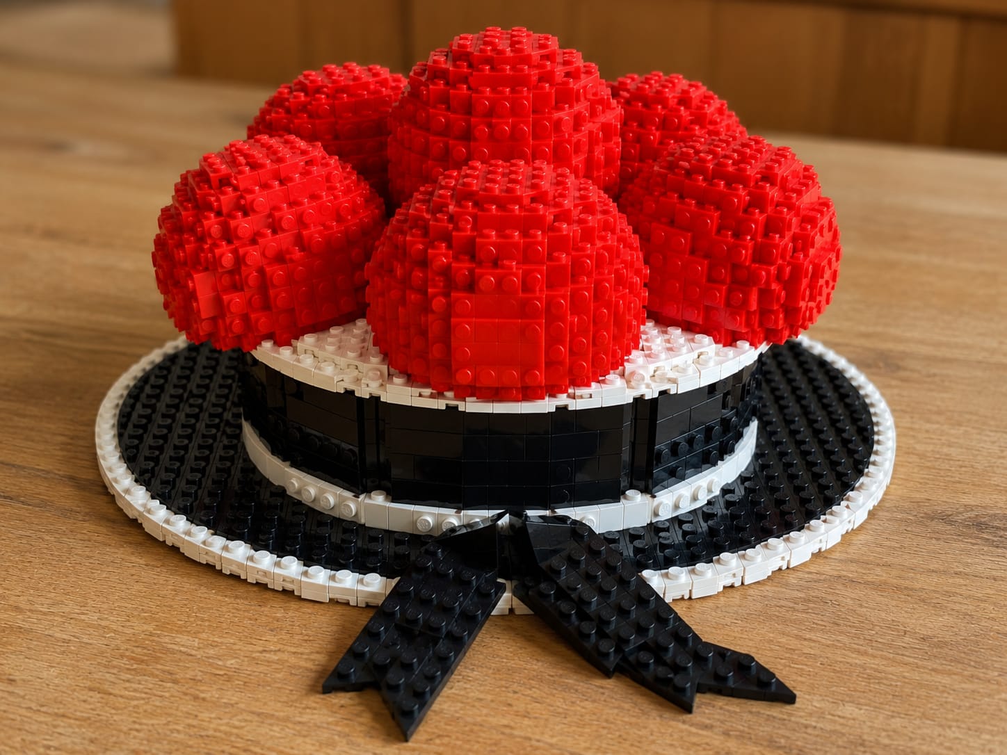 Bollenhut aus Klemmbausteinen mit roten Bollen auf schwarzem Hut